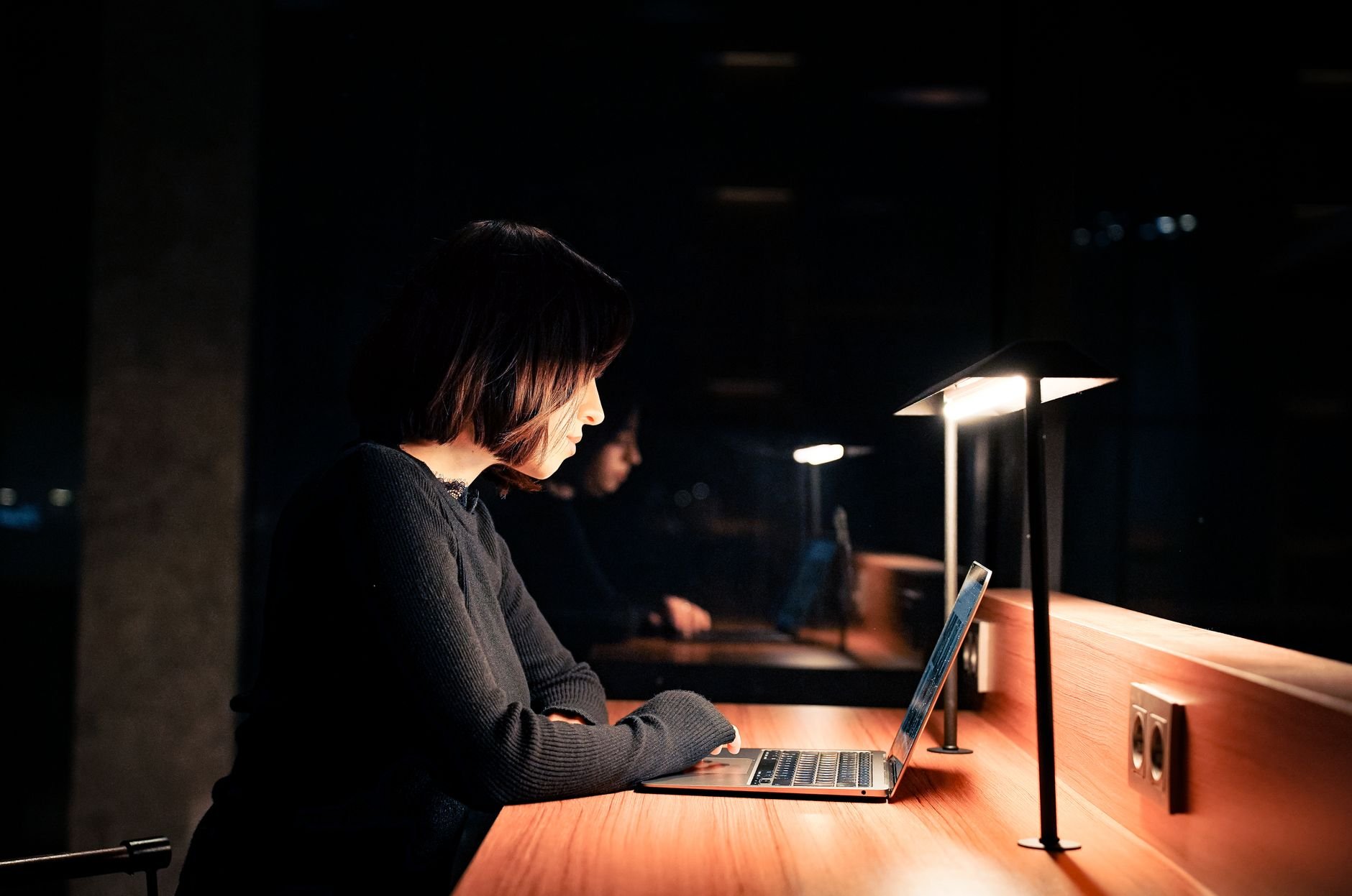 A founder working focused at a laptop in a dim office environment late at night